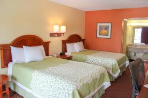 two beds in a hotel room with orange walls at Rose Garden Inn & Suites Thomasville in Thomasville