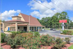 a building with an american flag on a street at Rose Garden Inn & Suites Thomasville in Thomasville