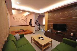 a living room with a green couch and a television at Seasons Homestay in Xiaoliuqiu