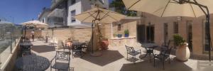 un patio con sillas, mesas y una sombrilla en Marom Residence Romema, en Haifa