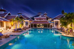 a swimming pool in front of a resort at night at Achawalai Residence Village By Song in Jomtien Beach