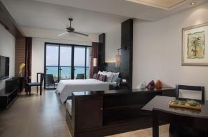 um grande quarto de hotel com uma cama e uma sala de estar em Ramada Plaza by Wyndham Sanya Bay em Sanya