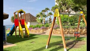 un parque infantil con tobogán y columpio en MI CAPRICHO 172 Beachfront Apartment, en Sitio de Calahonda