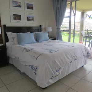 a bedroom with a large white bed with blue pillows at Laguna 75 in Uvongo Beach