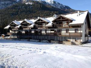 un edificio con neve sul terreno di fronte a una montagna di Residence Contrin a Canazei