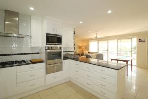 a kitchen with white cabinets and a living room at Barefoot, 32 Skyline Crescent, Crescent Head in Crescent Head