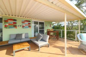 a pergola on a patio with chairs and a table at Barefoot, 32 Skyline Crescent, Crescent Head in Crescent Head