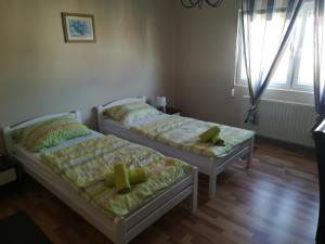 two beds in a room with two windows at Apartman Srce in Daruvar