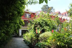un sentiero in mattoni di fronte a un edificio rosso di ROKPA Guest House a Kathmandu