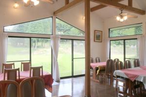a dining room with tables and chairs and large windows at Bellbird in Aso
