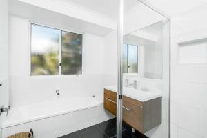 a white bathroom with a sink and a mirror at A SWEET ESCAPE - Serenity on Sallywattle in Suffolk Park