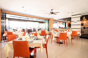 a restaurant with white tables and orange chairs at Vogue Pattaya Hotel in Pattaya