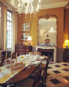 una sala da pranzo con tavolo e grande specchio di Chambre d'hôte Manoir de Clairbois a Larçay