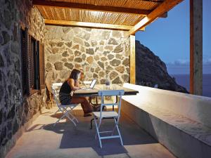 a woman sitting at a table with a laptop at Dammuso sulla scogliera - Pantelleria in Scauri