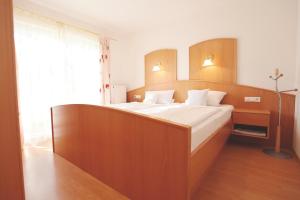 Schlafzimmer mit einem großen Bett mit einem Kopfteil aus Holz in der Unterkunft Haus Hildegunde in Bad Füssing