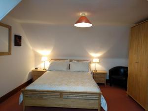 a bedroom with a bed with two lamps and a chair at Sandend Cottage in Banff