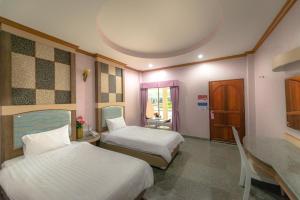 a hotel room with two beds and a table and a dining room at Martina Hotel Surin in Surin