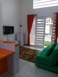 sala de estar con sofá verde y TV en Vila Monex en Batu