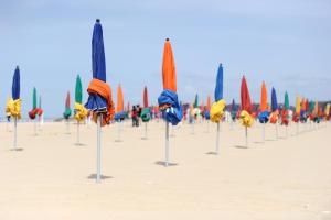 a row of different colored umbrellas on the beach at The golden triangle Apartment in Deauville