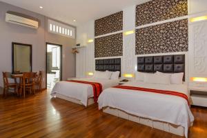 ein Hotelzimmer mit 2 Betten und einem Tisch in der Unterkunft Jonker Boutique Hotel in Malakka