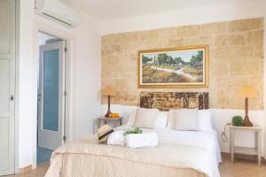 una camera da letto con un letto bianco e un dipinto sul muro di B&B Aurora Salentina a Morciano di Leuca