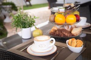 a table with a cup of coffee and bread and fruit at B&B Aurora Salentina in Morciano di Leuca +68 photos