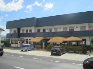 budynek z parasolami i samochodami zaparkowanymi przed nim w obiekcie Hotel O'Scugnizzo 2 w mieście Belluno