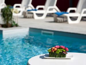 a small flower arrangement on a table next to a pool at Hotel Bikini in Rimini