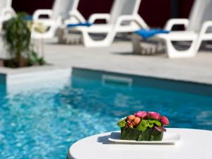 een klein bloemstuk op een tafel naast een zwembad bij Hotel Bikini in Rimini