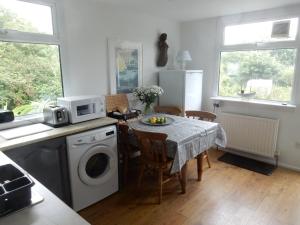 a kitchen with a table with a washing machine at Fuchsia Cottage in Porthallow