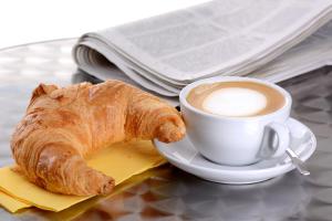 a cup of coffee and a croissant on a table at Casa Cinema Paradiso in Cefalù