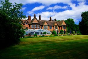 a large brick house on a grassy field at Stanhill Court Hotel in Charlwood