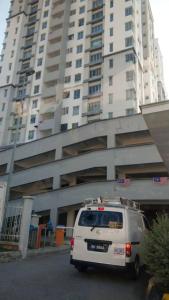 una furgoneta blanca estacionada frente a un edificio alto en Affordable Stay @ Rue’s Villa Tropika Apartment, UKM Bangi en Bangi