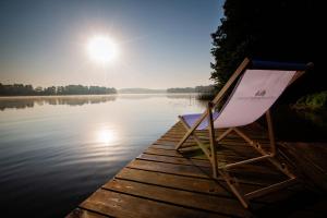 a chair sitting on a dock on a body of water at Winiec Family Houses in Winiec