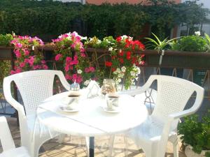 una mesa blanca y sillas con flores en el balcón en Guest House Izola, en Izola