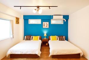 2 Betten in einem Zimmer mit blauer Wand in der Unterkunft Douce in Ginowan