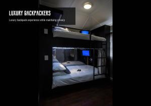 a room with two bunk beds in a dark room at Luxury Backpackers in Port Elizabeth