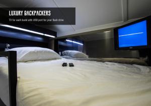 a large bed with a flat screen tv on it at Luxury Backpackers in Port Elizabeth