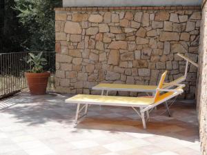 a bench and a table in front of a stone wall at Nascar Hotel in Santa Maria Navarrese