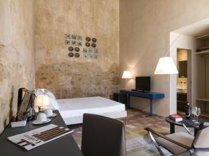 Schlafzimmer mit einem Bett und einem Schreibtisch mit einem Computer in der Unterkunft Wine Relais Feudi Del Pisciotto in Niscemi