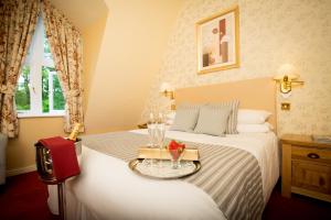 a hotel room with a bed with a tray of wine glasses at Glen-Yr-Afon House Hotel in Usk +45 photos
