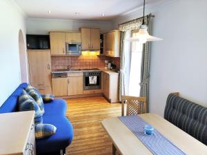 a living room with a blue couch and a kitchen at Urlaub am Bauernhof Rothof in Sankt Johann im Pongau