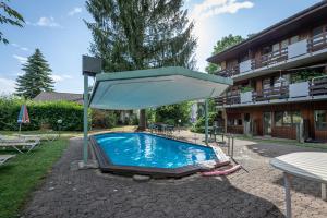 a swimming pool with a large umbrella next to a building at Noah Hotel in Rüti