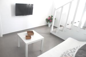 ein Wohnzimmer mit einem weißen Tisch und einem TV in der Unterkunft Apartamento Gaviotas in Tarifa
