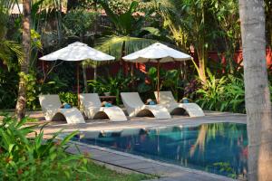 a pool with lounge chairs and umbrellas next to a pool at Maison Polanka in Siem Reap