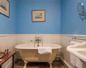 ein Badezimmer mit einer weißen Badewanne und einem Waschbecken in der Unterkunft Hostellerie La Montagne in Colombey-les-deux-Églises