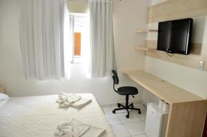 Habitación con cama, escritorio y TV. en Soder Hotel en Santa Cruz do Sul