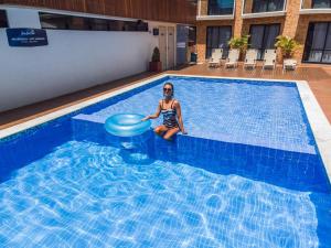 a woman sitting in a pool with a frisbee at Bessa Beach Hotel in João Pessoa