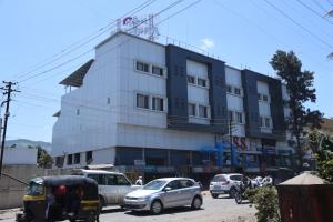 a building with cars parked in front of it at Hotel Pushpak in Satara