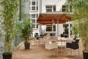 a patio with tables and chairs and an umbrella at MEININGER Hotel Berlin Mitte in Berlin